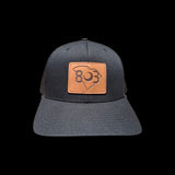 803 Yupoong Black/Black Leather Patch Trucker